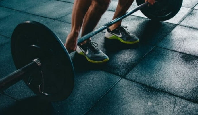 Person hebt eine Langhantel im Fitnessstudio.